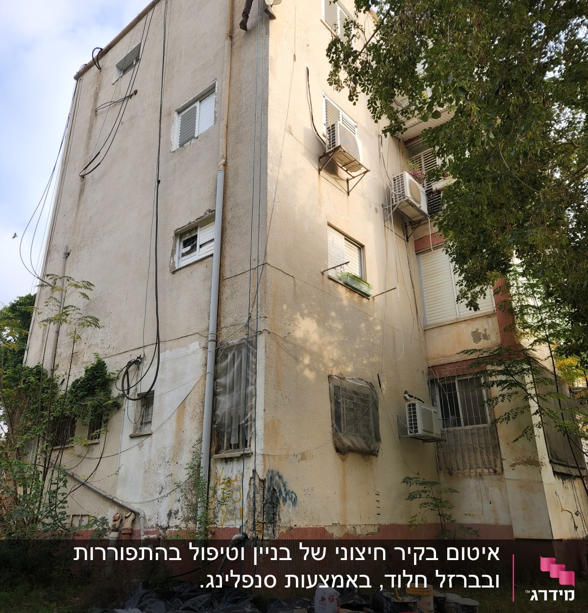 אדם על חבל צובע קיר בניין עם דלי צבע